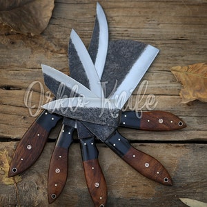 May include: A collection of handcrafted knives with dark wooden handles and textured blades arranged in a circular pattern. The blades have a silver finish, and the handles are a rich brown with decorative rivets. The knives are displayed on a rustic wooden surface.