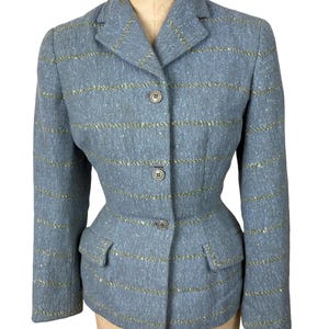 May include: A vintage blue blazer with horizontal gold stripes, three buttons, and two front pockets. The tailored jacket is displayed on a mannequin. The blazer has a classic, fitted silhouette.