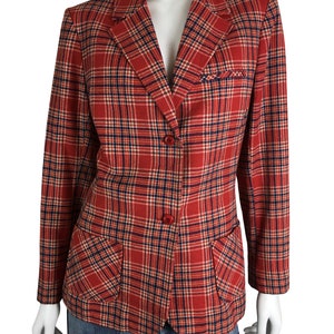 Könnte beinhalten: Ein roter, blauer und weißer karierter Blazer mit zwei Pattentaschen. Der Blazer hat einen einzigen Knopfverschluss.