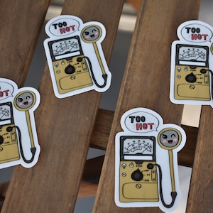 Könnte beinhalten: Vier Aufkleber mit einer Cartoon-Illustration eines Geigerzählers im Vintage-Stil mit einer lächelnden Sonde. Der Text "Too Hot" befindet sich in einer Sprechblase über dem Zähler.