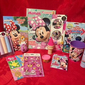 Puede incluir: Una colecci&oacute;n de juguetes y libros para ni&ntilde;os con el tema de Minnie Mouse. Los art&iacute;culos incluyen un libro para colorear, un libro de pegatinas, un paquete de juego, una taza, un producto de ba&ntilde;o, crayones, tiza y una varita de burbujas.
