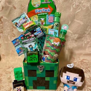 May include: A Minecraft-themed gift basket filled with toys and candy. The green box features a pixelated design, and includes a plush toy, a green Creeper head, and a variety of Minecraft-branded items, including a Play Pack and Skittles.