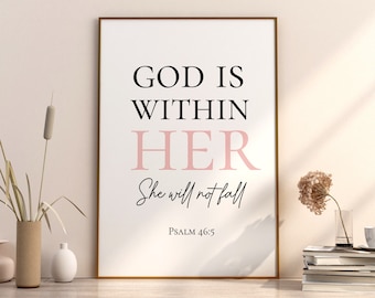 May include: A framed print with a white background and black text that reads "GOD IS WITHIN HER She will not fall PSALM 46:5". The word "HER" is in pink. The print is framed in a gold frame and is sitting on a white surface.