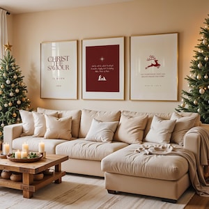 May include: A living room decorated for Christmas, featuring a beige sectional sofa, a wooden coffee table, and two Christmas trees. Three framed prints with text and a reindeer graphic are displayed above the sofa. Candles and decorations create a festive ambiance.