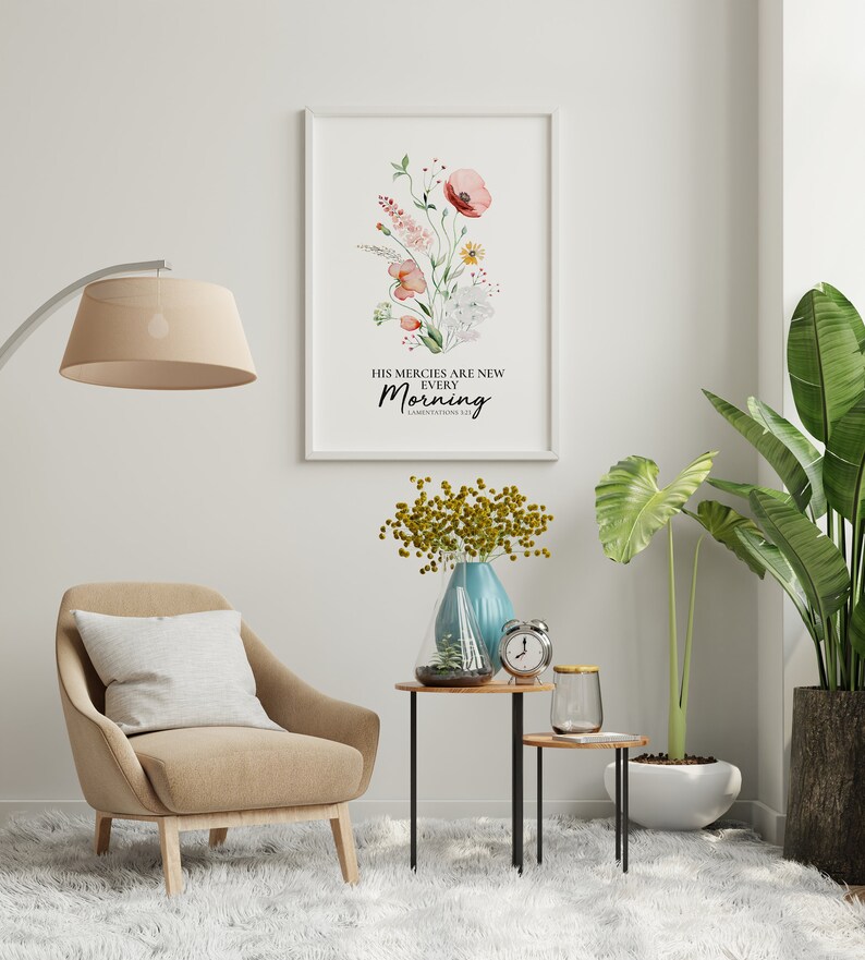 May include: A watercolour print featuring a floral design and the text "His mercies are new every morning. Lamentations 3:23". The print is framed and hanging on a white wall in a living room setting.