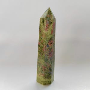 May include: A white ceramic mug with a black handle and the text "But First, Coffee" in a handwritten style. The mug is on a white surface. The mug is likely for hot beverages.