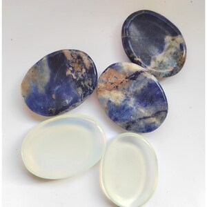 Pu&ograve; includere: Assortimento di pietre ovali levigate in vari colori, tra cui rosa, marrone, blu, bianco, verde e viola. Le pietre sono lisce e hanno una finitura naturale e lucida.