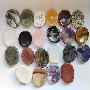 Pu&ograve; includere: Assortimento di 18 pietre ovali lucidate in vari colori e motivi. Le pietre sono disposte a semicerchio su una superficie bianca.