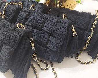 May include: A group of five black crocheted handbags with gold chain straps and black tassels. The handbags are made with a woven pattern.