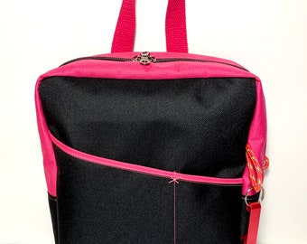 May include: A black backpack with a pink zipper and pink trim. The backpack has a single top handle and a small pocket on the front.
