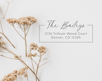 May include: A white background with the text "The Baileys" in elegant script above an address: 1234 Trillium Wood Court, Denver, CO 12345. Dried floral stems with beige blossoms are arranged around the text.