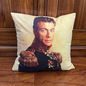 Puede incluir: Una almohada decorativa con una imagen de estilo vintage de un hombre con uniforme militar. El hombre tiene el pelo oscuro y una expresión seria. La almohada es beige con una textura sutil.