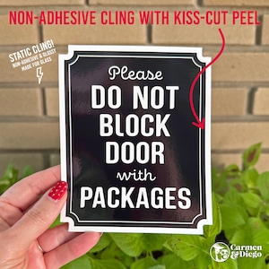 May include: A rectangular black static cling sign with a white border and white text that reads: Please DO NOT BLOCK DOOR with PACKAGES. The sign features a glossy finish and is designed for application on glass surfaces without adhesive.