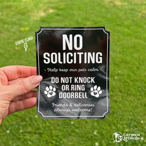 May include: Black and white sign with the text "NO SOLICITING" and "DO NOT KNOCK OR RING DOORBELL". The sign also says "Help keep our pets calm" and "Friends & deliveries always welcome!" The sign has a static cling backing.
