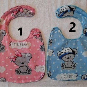 Peut inclure: Deux bavoirs pour bébé, un rose avec un ours en peluche gris et le texte "C'est une fille !" et l'autre bleu avec un ours en peluche gris et le texte "C'est un garçon !"