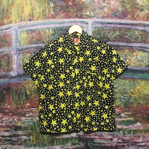 May include: A black short-sleeved button-up shirt with a yellow star pattern.