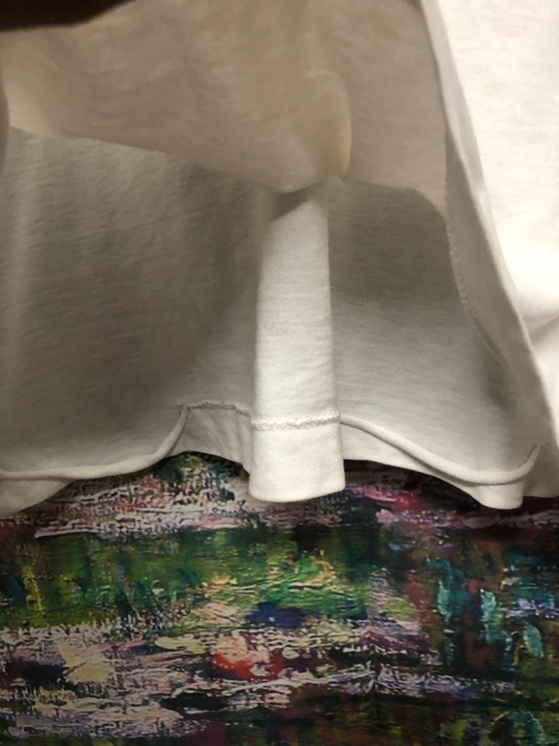 Puede incluir: Una camiseta blanca lisa con un dobladillo cosido.