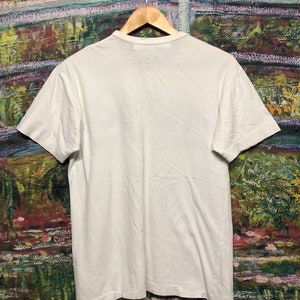 Puede incluir: Una camiseta blanca de manga corta con cuello redondo.