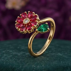 Peut inclure: Une bague ouverte en or avec un motif floral composé de pierres rouges taille poire entourant une pierre centrale transparente, complétée par une pierre verte taille poire à l'autre extrémité de l'anneau, avec une finition dorée polie.