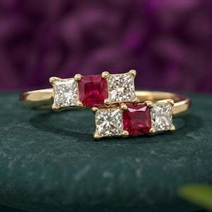 Puede incluir: Un anillo de oro con dos filas de piedras preciosas de corte princesa. Cada fila contiene un rubí rojo cuadrado central flanqueado por dos diamantes blancos transparentes cuadrados. La banda de oro amarillo pulido muestra un diseño simétrico.