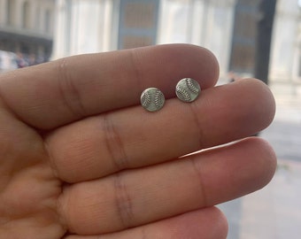 May include: A pair of silver baseball stud earrings. The earrings are small and round, with a raised baseball design.