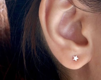 Puede incluir: Primer plano de una oreja con un pequeño pendiente de estrella de plata.