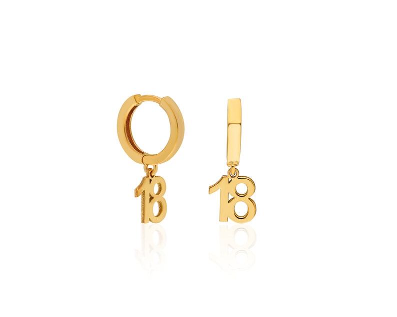 May include: Gold hoop earrings with a dangling charm of the number 18.