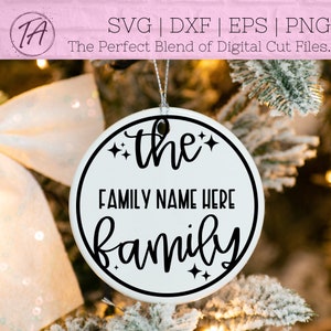 May include: A white round ornament with a black border and black text that reads "the FAMILY NAME HERE family" with small stars around the text.