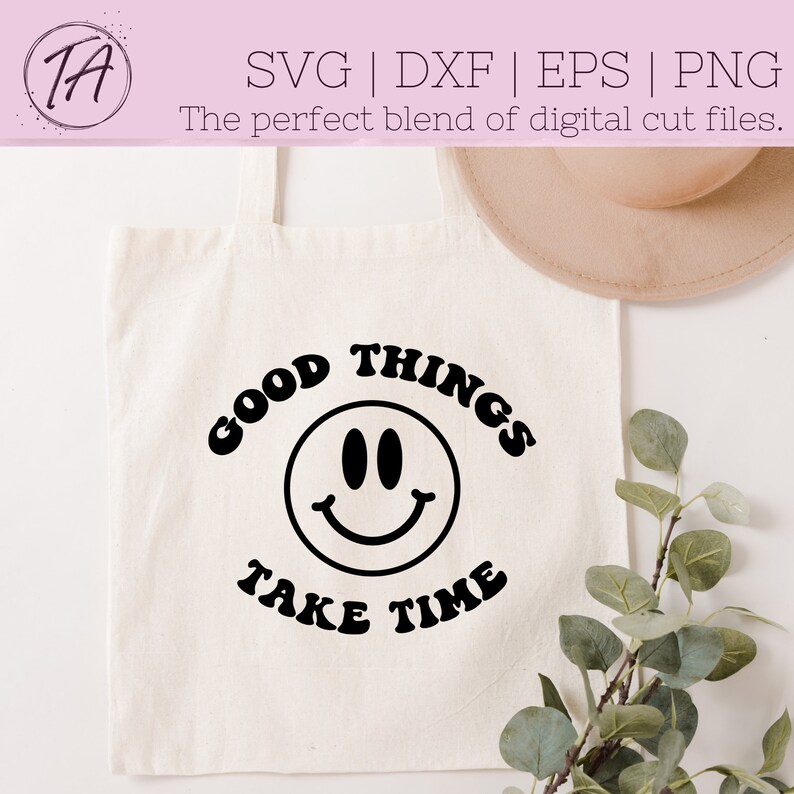 May include: A white tote bag with black text that reads "GOOD THINGS TAKE TIME" with a black smiley face in the center.
