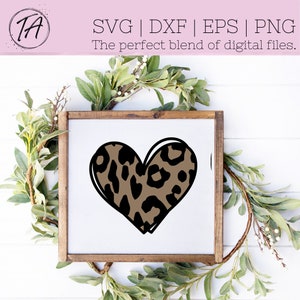 May include: A brown and black leopard print heart shape in a white frame with a brown wood border.