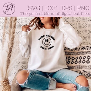May include: White sweatshirt with black text that reads "Good Things Take Time" and a black smiley face graphic.