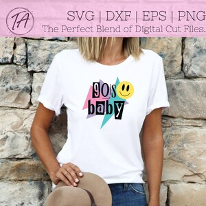 May include: White t-shirt with a graphic design that says "90's baby" with a pink, purple, and blue geometric design and a yellow smiley face.