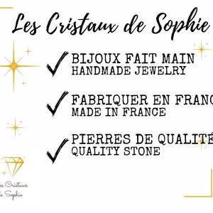 以下が含まれることがあります： 金色の星と金色の枠で囲まれた白い背景。テキスト「Les Cristaux de Sophie」は黒い筆記体で書かれています。テキストの下には、黒いフォントで書かれた3つのチェックマークがあります。「BIJOUX FAIT MAIN HANDMADE JEWELRY」、「FABRIQUER EN FRANCE MADE IN FRANCE」、「PIERRES DE QUALIT&Eacute; QUALITY STONE」。