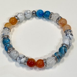 May include: A multi-colored beaded bracelet with white, orange, blue, and clear beads. The beads are separated by silver spacers with rhinestones.