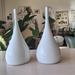 May include: Two white teardrop-shaped pendant lights with a modern design.