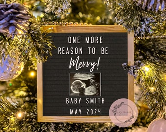 May include: A square black felt letter board with a light wood frame displaying the white text ONE MORE REASON TO BE Merry! followed by a black and white ultrasound image, the text BABY SMITH, and the date MAY 2024, centered on the board.