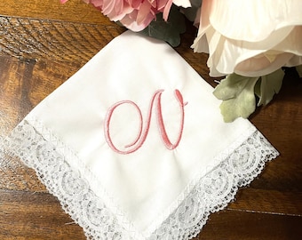 May include: White handkerchief with a lace border and a pink embroidered letter N.