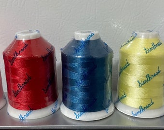 May include: Five spools of embroidery thread in pink, red, blue, yellow, and purple. Each spool is labeled "Simthread".