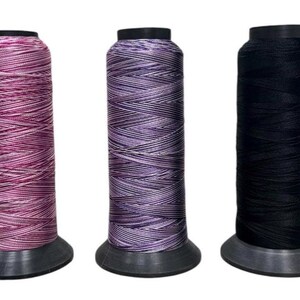 May include: Three spools of thread, one pink and white, one purple and white, and one black. The spools are all on a white background.