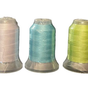 May include: Six spools of thread in different colors: white, light blue, blue, green, and orange. The spools are all the same size and shape, and they are all in clear plastic containers.