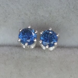 Puede incluir: Un par de pendientes de plata con una piedra preciosa redonda azul en cada uno.
