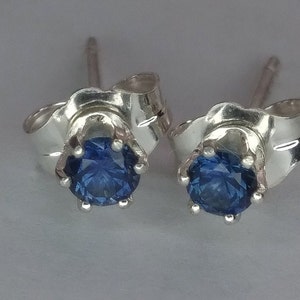 Puede incluir: Un par de pendientes de plata con una piedra preciosa azul en cada uno. Los pendientes tienen un dise&ntilde;o simple y elegante.