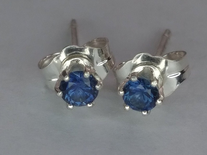 Puede incluir: Un par de pendientes de plata con una piedra preciosa azul en cada uno. Los pendientes tienen un dise&ntilde;o simple y elegante.