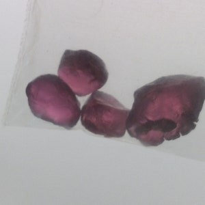 May include: Four small, faceted, purple gemstones in a clear plastic bag.