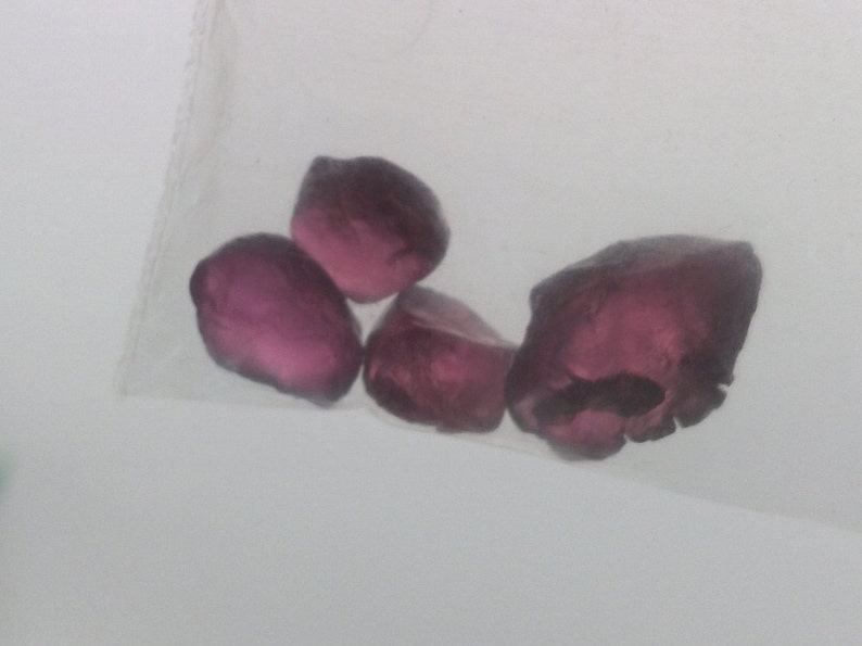May include: Four small, faceted, purple gemstones in a clear plastic bag.