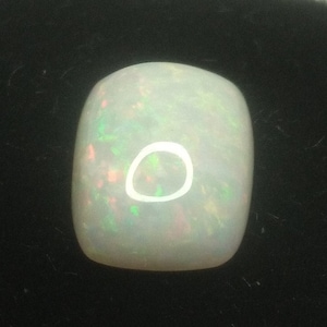 Peut inclure: Une pierre précieuse d'opale blanche avec un éclat iridescent vert clair et rose.