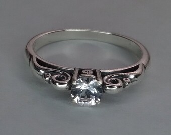 Danburite ring.  Scroll style band. Rhodium plated silver ring in size 7. Faceted Danburite is 4.5mm at 0.33ct