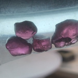 May include: Four small, faceted, purple gemstones in a clear plastic bag.