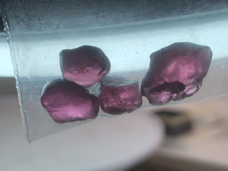 May include: Four small, faceted, purple gemstones in a clear plastic bag.