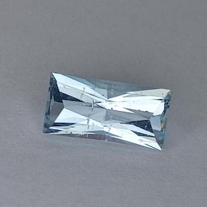 May include: A light blue aquamarine gemstone with a rectangular cut and a faceted design.